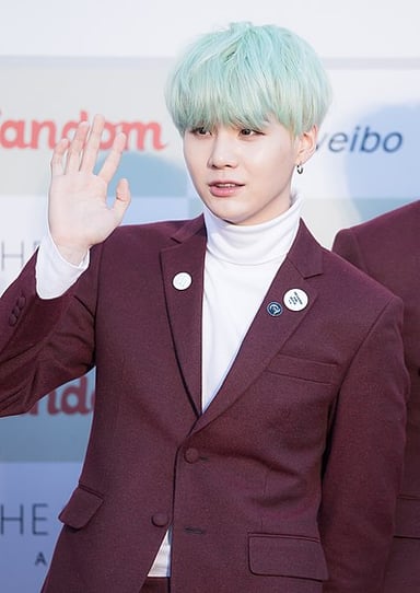 Which BTS bandmate does Suga tie with as the highest-charting South Korean solo artist?