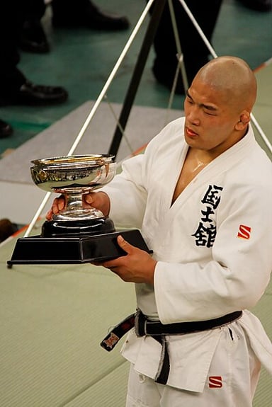 In addition to judo, Ishii also has a black belt in what?