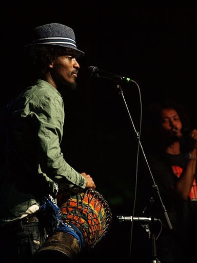 What instrument does K'naan often accompany his rap verses with?