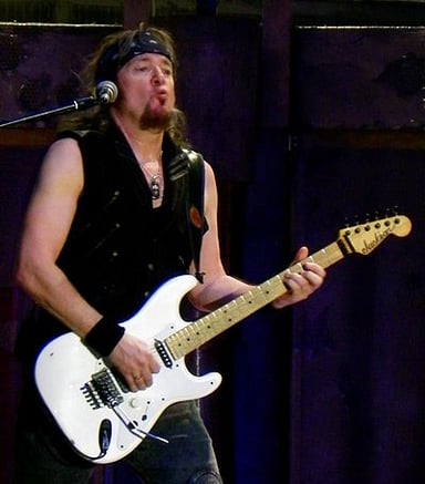 Which band is Adrian Smith best known for playing in?