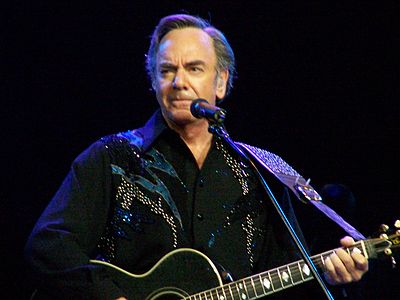 What musical instrument does Neil Diamond typically play while performing?