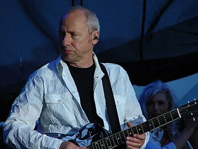 What distinctive style of guitar playing is Mark Knopfler known for?