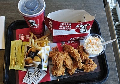 Who introduced the cardboard "bucket" for serving larger portions of fried chicken at KFC?