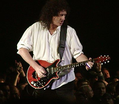 What is the name of the blues rock band Brian May performed with before Queen?