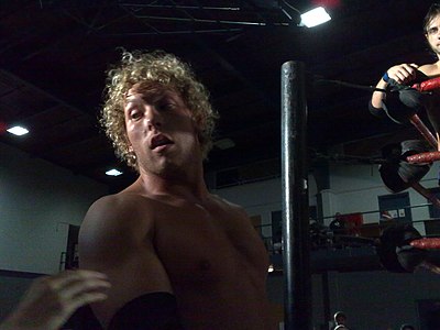 Which wrestling promotion is Kenny Omega currently signed with?